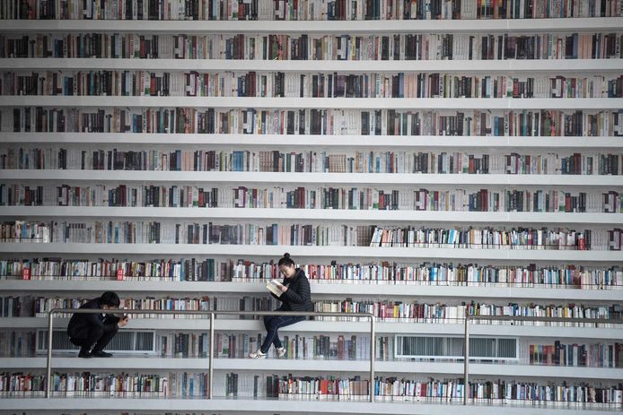 This picture taken on November 14, 2017 shows a woman reading a book at the Tianjin Binhai Library.
A futuristic Chinese library has wowed book lovers around the world with its white, undulating shelves rising from floor to ceiling, but if you read between the lines you'll spot one problem. Those rows upon rows of book spines are mostly images printed on the aluminium plates that make up the backs of shelves. / AFP PHOTO / FRED DUFOUR / To go with AFP story China-library-architecture, FOCUS by Becky Davis