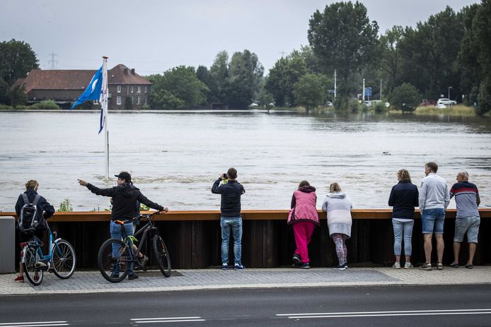 Mensen staan te kijken naar het hoge water in de Maas. Het hoge water wordt met name veroorzaakt door enorme regenbuien in het stroomgebied van de Maas in Belgie en de Ardennen.