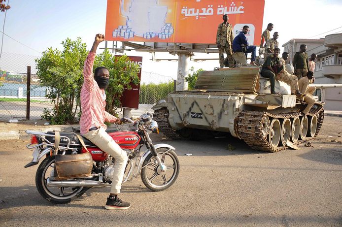 Een man heft zijn vuist op terwijl hij langs Soedanese legersoldaten rijdt in de Soedanese stad Port Sudan.