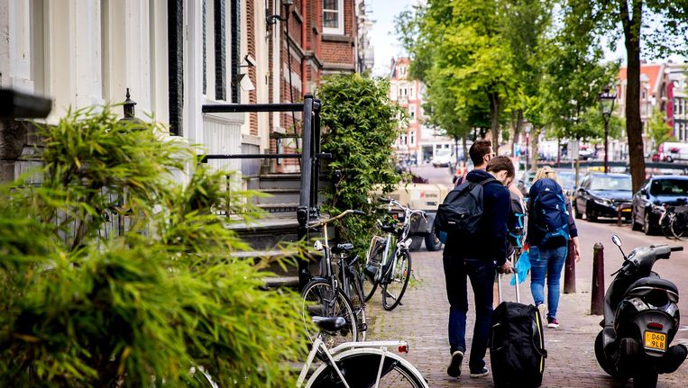 Toeristen met rolkoffers op de grachten in Amsterdam. Beeld ANP