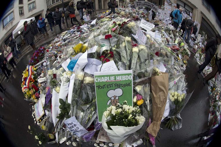 De nieuwe Charlie Hebdo tussen de bloemen voor het kantoor in Parijs. Beeld afp