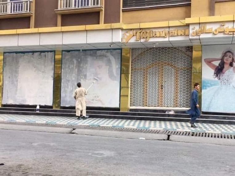Een man beschildert de beeltenissen van vrouwen in het straatbeeld ter voorbereiding op de komst van de taliban. Beeld Twitter/Lotfullah Najafizada