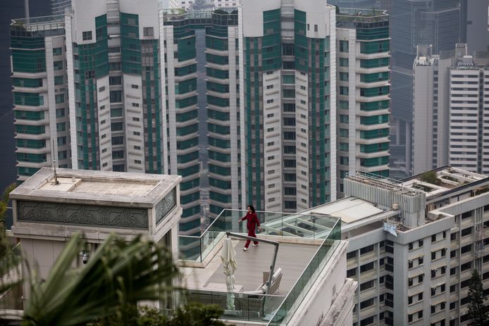 Een Chinese vrouw loopt een rondje op het terras van haar appartement in een dure wijk van Hong Kong. Foto Jerome Favre
