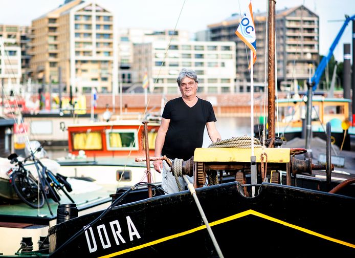 Oud en nieuw in Nijmegen-West: Eric Mol op zijn woonschip in de Waalhaven en op de achtergrond de nieuwbouw van de Handelskade.