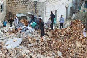 Burgers in het Syrische dorp Datat Izza bekijken de schade na een Russische luchtaanval woensdag.