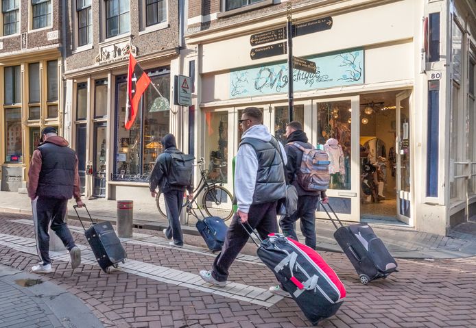 Toeristen met rolkoffers op de Zeedijk in Amsterdam.