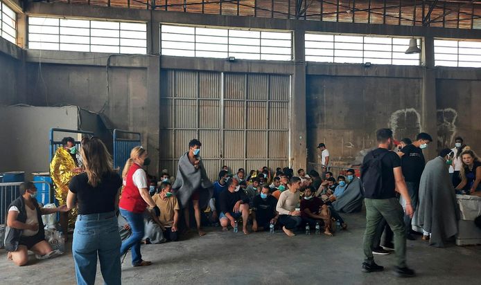 Overlevenden van de schipbreuk zitten in een magazijn in de haven van Kalamata, Griekenland.