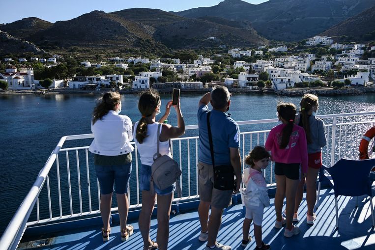 Reizigers maken foto's van het Griekse eiland Tilos vanop hun ferry. Beeld AFP