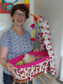 Hennie (67) met het gerepareerde 65 jaar oude poppenwiegje. ,,Ik heb alle materialen gekregen en het opknappen heeft me geen cent gekost.”