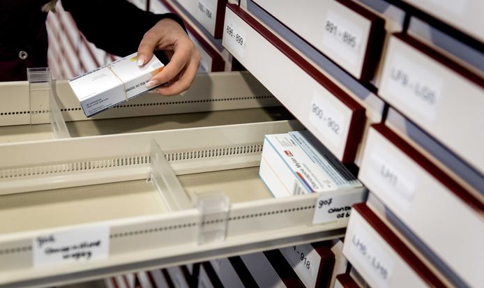 Een apothekersassistente zoekt medicijnen bij elkaar in een apotheek.