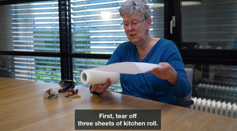Zelf een mondkapje maken met keukenpapier. Beeld uit een instructievideo van Buurtzorg Nederland.  Beeld *