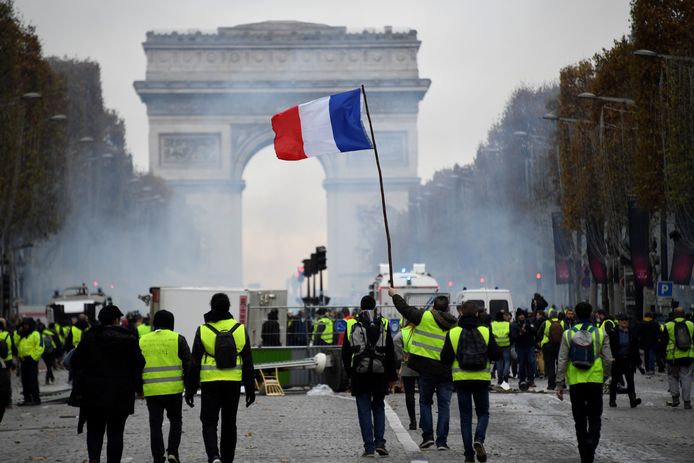 Demonstranten zwaaien met de Franse vlag bij een barricade op de Champs-Elysées.