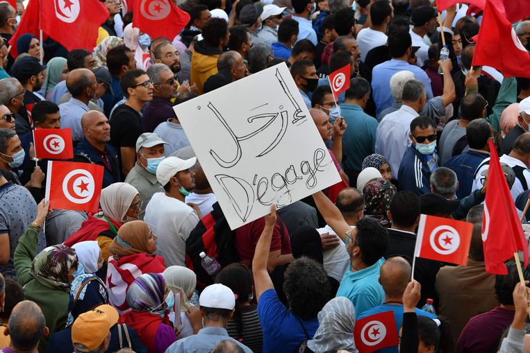 Tunesiërs hijsen bij het Habib Bourguibaplein nationale vlaggen tijdens een demonstratie tegen president Kais Saied. Beeld AFP