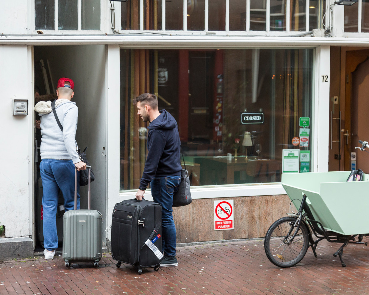 Toeristen komen in het centrum van Amsterdam aan op het logeeradres dat ze via Airbnb hebben geboekt. Beeld Hollandse Hoogte / Bert Spiertz