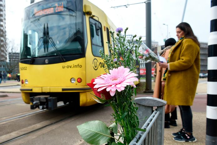 De tram rijdt weer over het 24 Oktoberplein. Omstanders leggen bloemen neer.