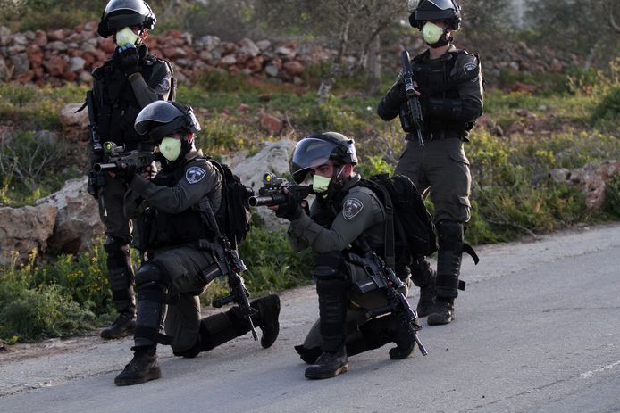 Israëlische soldaten richten hun wapens op Palestijnse betogers.