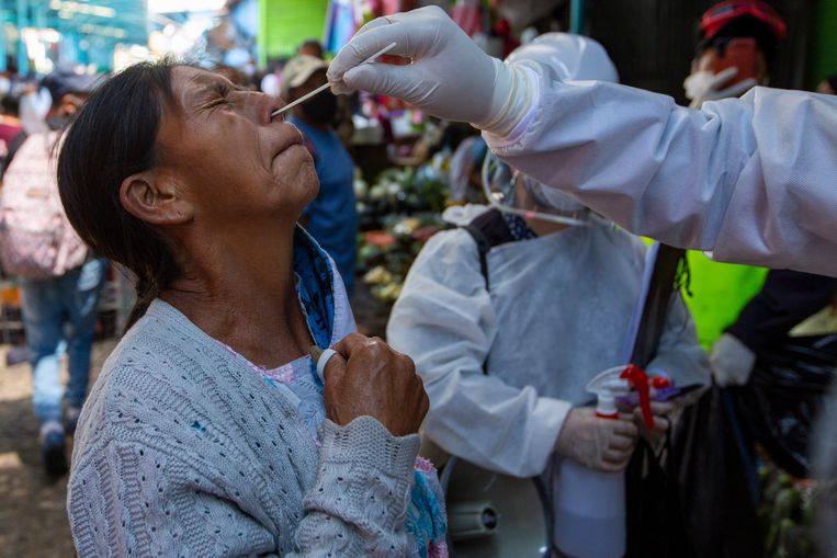 Medewerkers van het ministerie van Volksgezondheid testen verkopers op een markt in Guatemala-Stad of ze corona hebben Beeld AP
