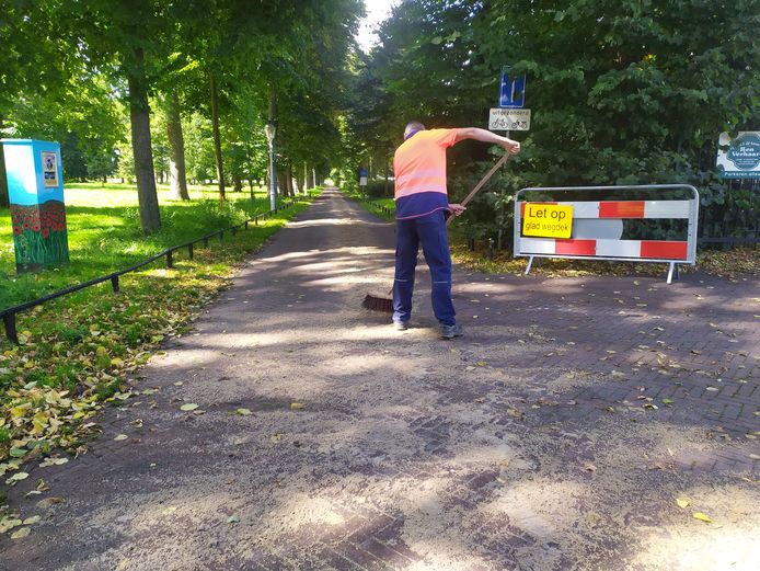 Een medewerker van het Groenbedrijf verspreidt het zand over de weg in het Worpplantsoen.