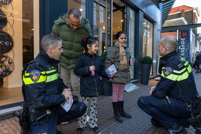 Wijkagent Alex Glijn deelt in Schiedam aan kinderen bonnen uit voor goed gedrag.