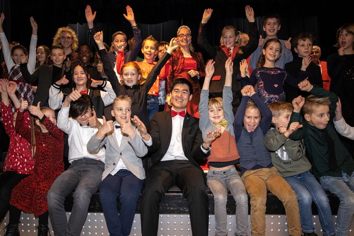 Wim Steenbakker (midden, met rode strik) tussen zijn muzikanten op het podium van De Wemel in Wemeldinge.