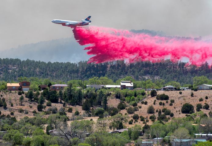 Een blusvliegtuig dropt een brandvertragend middel over een woongebied in New Mexico.