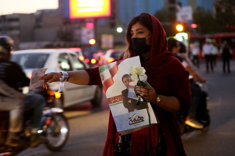 Een aanhanger van de hervormingsgezinde Abdolnaser Hemmati deelt folders en bloemen uit in Teheran, 16 juni. Beeld Fatemeh Bahrami / Anadolu / Getty