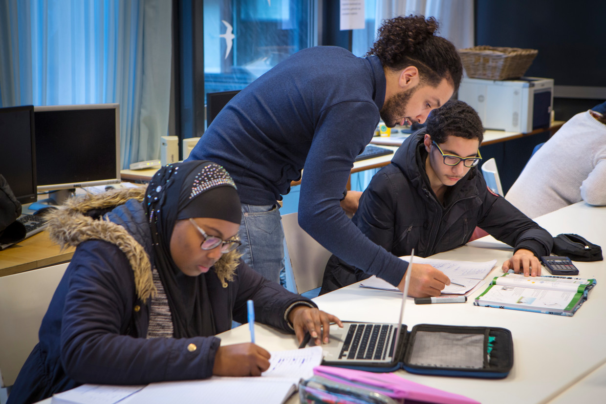Nadir Kaddouri (staand) geeft huiswerkbegeleiding. 'Geld mag geen drempel zijn', vinden hij en zijn collega Darine el Houfi. Beeld Jorgen Caris