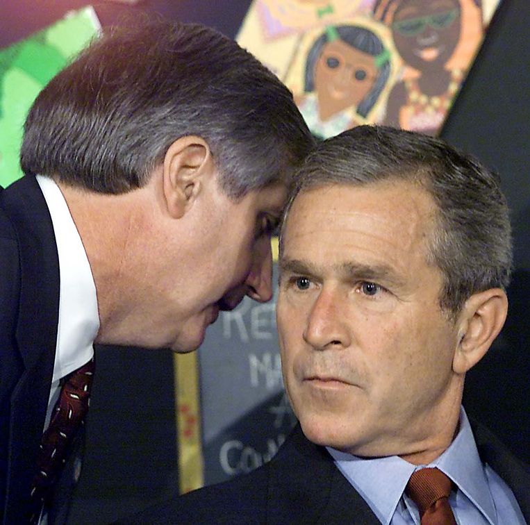 Het moment dat president George W. Bush (r) hoorde dat twee vliegtuigen zich in de Twin Towers hadden geboord. Hij was op een school kinderen aan het voorlezen.  Beeld AFP
