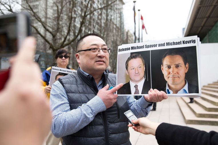 Een lid van de vereniging Vancouver Freedom and Democracy for China houdt foto's omhoog  van de Canadezen Michael Spavor en Michael Kovrig die vastgehouden worden in China. Spavor is vandaag in China veroordeeld tot elf jaar cel voor spionage.  Beeld AFP