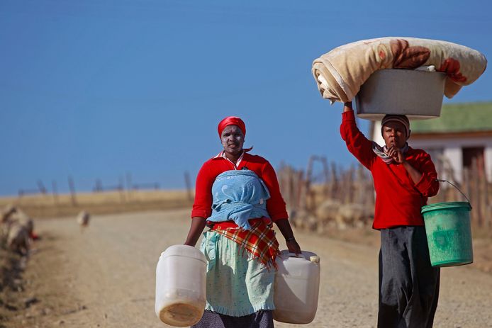 Vrouwen dragen water en dekens naar hun huis in Mvezo, Zuid-Afrika.