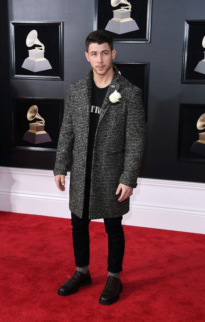 Nick Jonas met een witte roos op zijn lange jas.