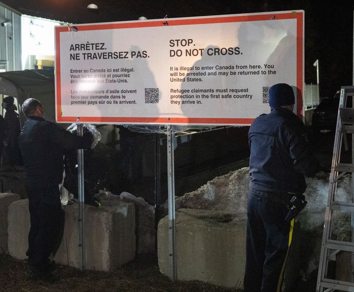 Agenten van de Canadese Royal Canadian Mounted Police plaatsen een bord waarop asielzoekers gewaarschuwd worden de grens niet illegaal over te steken.