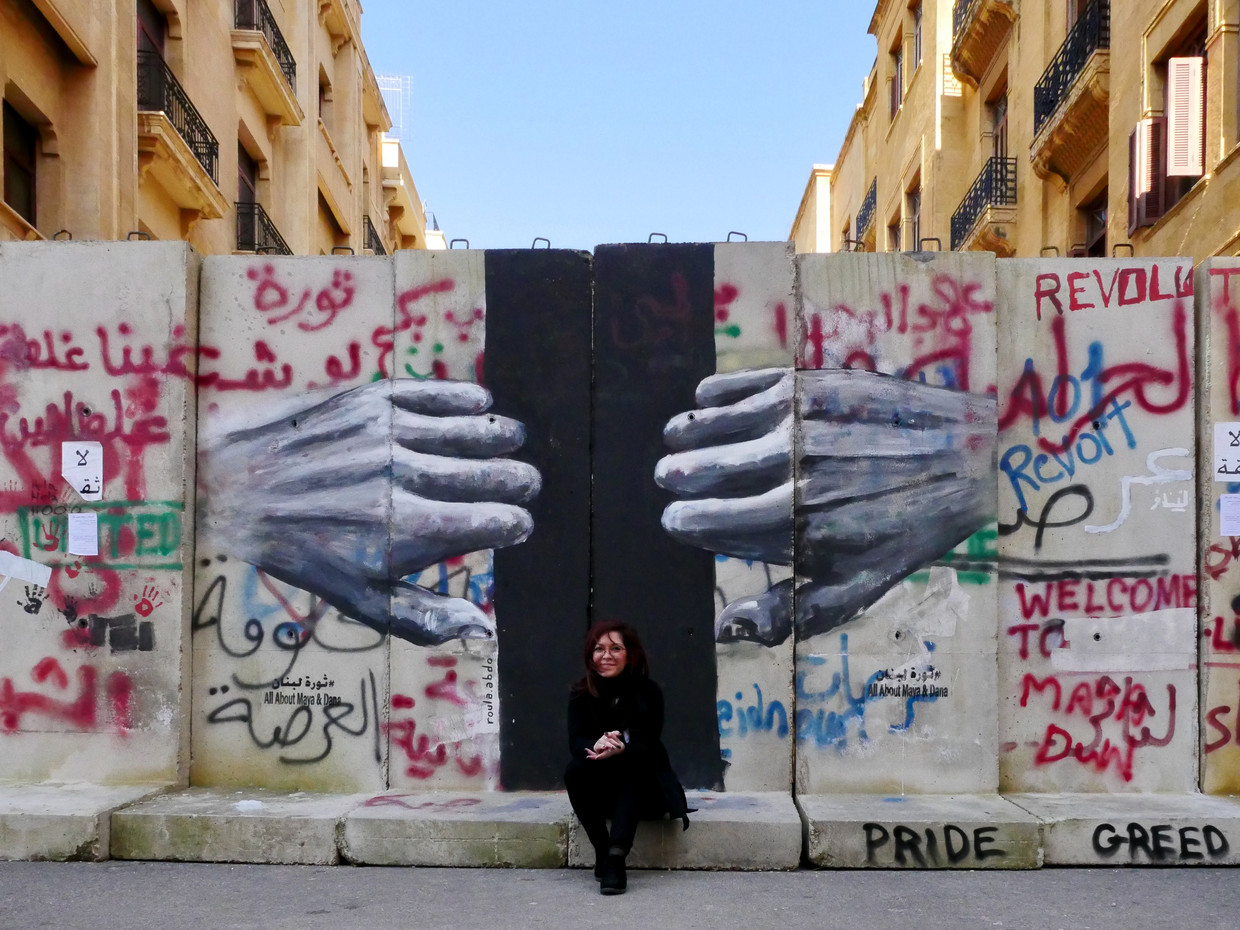 Roula Abdo aan haar muurschildering in Beiroet. “We willen de demonstranten motiveren en een artistieke kant van de revolutie te laten zien.” Beeld Bruno Struys