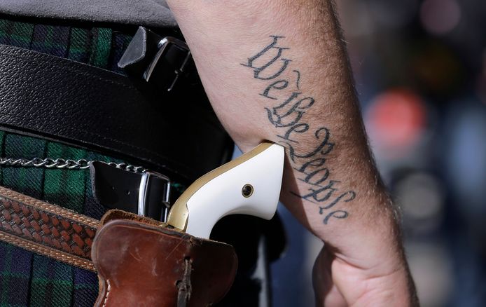 Een man draagt openlijk een pistool in Texas. Op zijn arm staan de eerste woorden van de Amerikaanse grondwet: 'We the people', 'wij, het volk'.