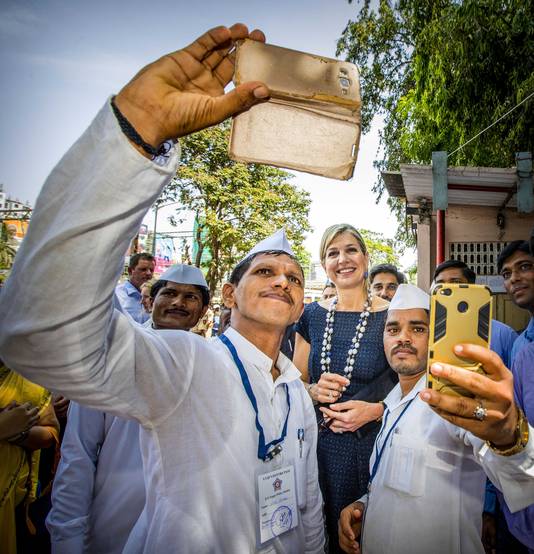 Twee maaltijdbezorgers maken een selfie met onze koningin Máxima