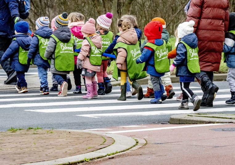Kinderen die verblijven in een kinderopvang steken onder begeleiding een straat over via het zebrapad. Beeld ANP / Robin Utrecht