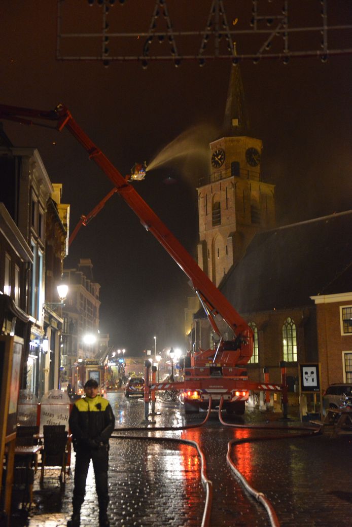 De brandweer probeert de kerktoren nat te houden zodat de brand niet overslaat.