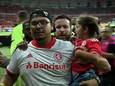 Internacional-fan gaat spelers van Caxias te lijf met jong meisje op de arm.