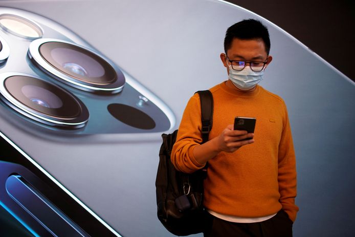 Een man met een iPhone 12 in Shanghai.