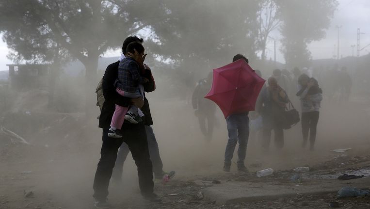 Syrische vluchtelingen beschermen zich tegen windhozen terwijl ze de Griekse grens met Macedonië oversteken. Beeld reuters