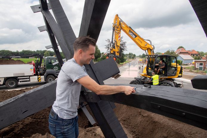 Jan Willem ten Beitel kwast het laatste stukje van het grote waterrad zwart. Het kunstwerk is maandagochtend geplaatst op nieuwe rotonde Haaksbergseweg / N315.