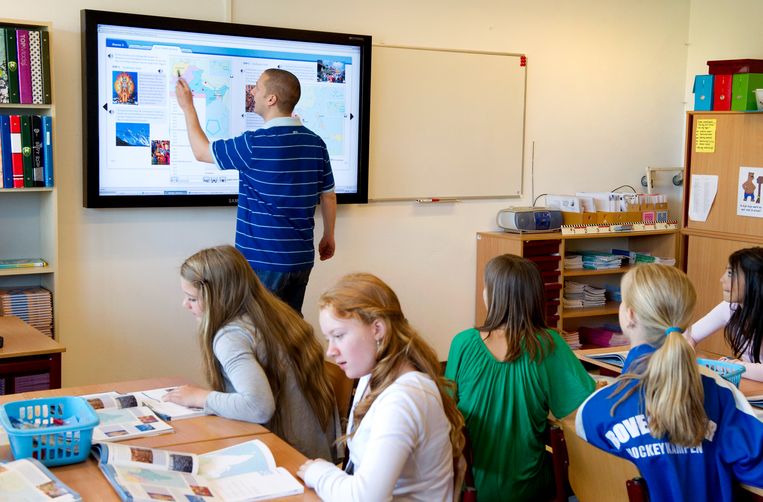 Een leraar geeft uitleg aan de klas op een digitaal schoolbord. Beeld Lex van Lieshout, ANP