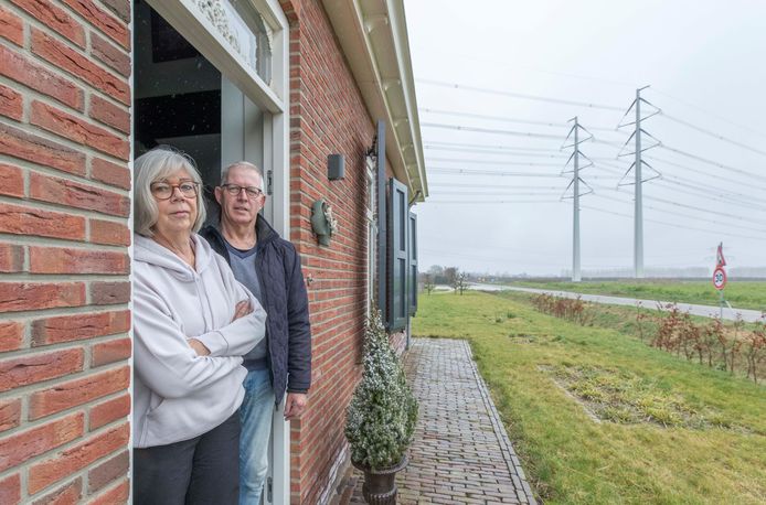 Frieda en Piet van der Does bij de voordeur van hun nieuwe woning bij Heinkenszand. De nieuwe lijn, op de achtergrond, loopt precies over de plek van hun vorige huis.