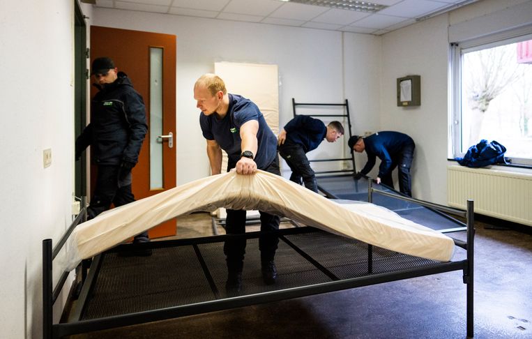 Een van de 500 noodbedden wordt in elkaar gezet in een van de ruimten op vliegveld Twente, waar een noodopvang voor vluchtelingen is geopend. Beeld Freek van den Bergh/ de Volkskrant