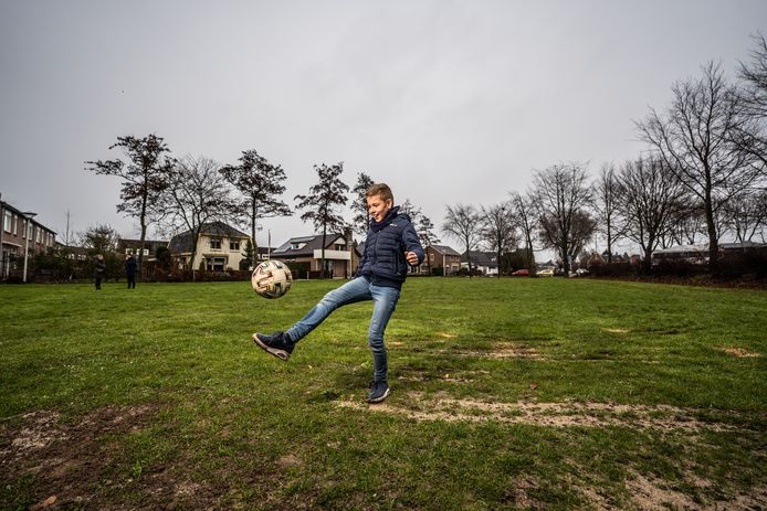 Florian de Beijer op het gras waar hij voor hem en zijn vrienden graag een omheind kunstgrasveld zou zien om op te kunnen voetballen.