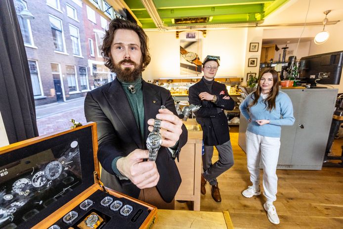 Michiel Holthinrichs toont een van zijn unieke ontwerpen, terwijl zijn collega's Damiaen en Tanja op de achtergrond poseren.