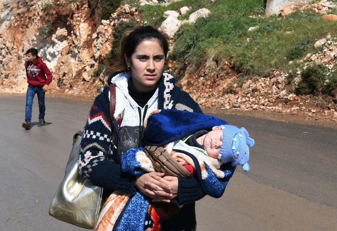 Een vrouw vlucht met haar baby uit Afrin.