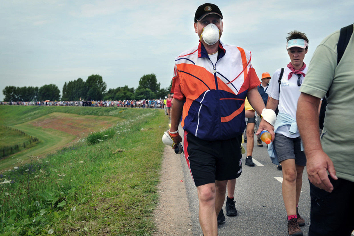 Een vierdaagse wandelaar heeft voor de zekerheid een mondkapje opgedaan. (Marcel van den Bergh/ de Volkskrant) Beeld 
