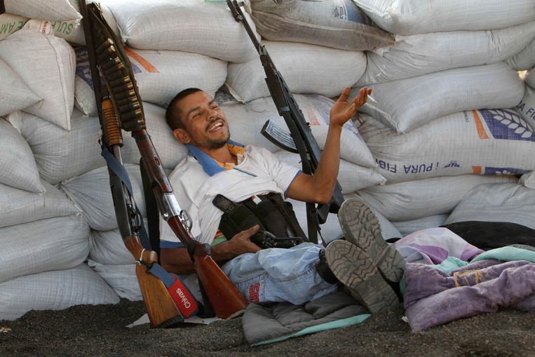 Een zwaarbewapend lid van een burgerwacht zit bij een versperring in de Mexicaanse deelstaat Michoacan. Beeld Marco Ugarte / AP