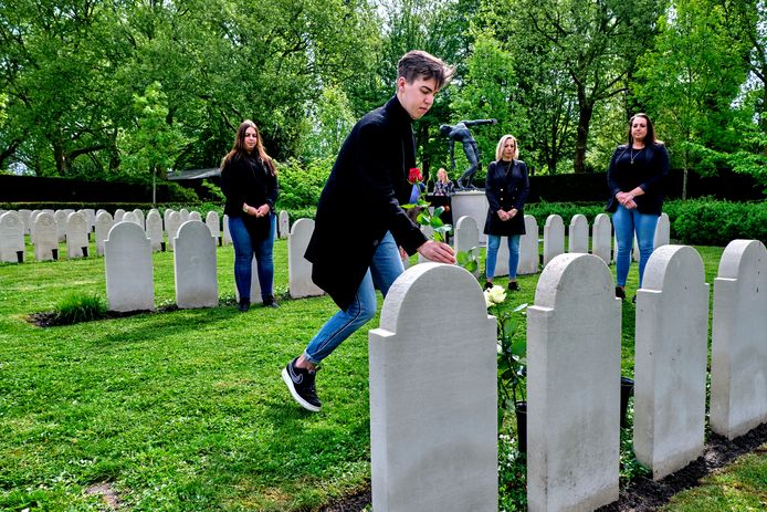 Kleinkinderen van verzetsman Leendert Keesmaat leggen ieder een roos op zijn graf, in mei 2020.